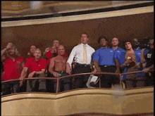 a group of men are standing in front of a balcony and one of them is wearing a shirt that has the letter y on it