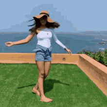 a woman in a hat is dancing on a rooftop overlooking the ocean .