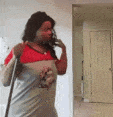 a woman is talking on a cell phone while holding a broom .