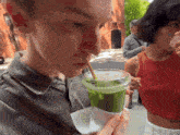 a man is drinking a green smoothie with a straw