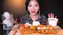 a woman is eating fried food with chopsticks and a glass of ice cubes