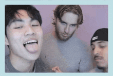 a man sticking his tongue out while two other men look on .