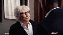 an older woman with glasses is talking to a younger man