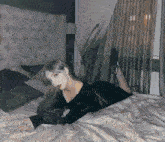 a woman in a black dress is laying on her back on a bed