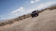 a red car driving down a desert road