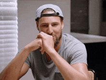 a man with a beard wearing a baseball cap and a grey shirt
