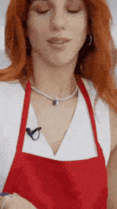 a woman with red hair wearing a red apron and a necklace .
