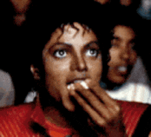 a man in a red shirt is eating something with his hands