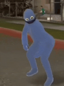 a person in a cookie monster costume is squatting down on the sidewalk .