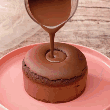 a chocolate cake is being poured with chocolate sauce on a pink plate
