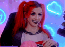 a woman with red hair is sitting in a chair in front of a neon sign and smiling .