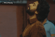 a man with a beard is looking up with x7wickreddy written on the bottom