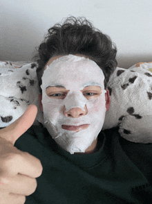 a young man with a white mask on his face gives a thumbs up