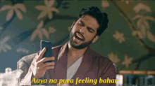 a man with a beard is laughing while looking at his phone with the words aaya na pura feeling bahar below him
