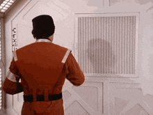 a man in a space suit is standing in front of a white wall .