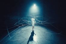 a woman in a white dress is standing in a dark room surrounded by spider webs