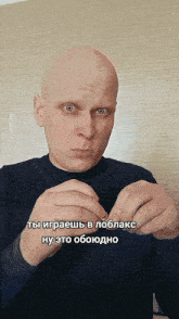 a bald man in a black sweater is holding something in his hands with a caption in russian