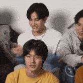 a group of young men are sitting next to each other on a couch .