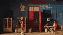 a woman in a red outfit is dancing in front of a blue building that says padaria