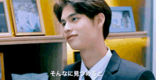 a man in a suit and tie is sitting in front of a shelf with pictures on it ..