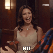 a woman in a tan dress is holding a box of chocolates and saying hi