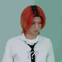 a man with red hair is wearing a white shirt and black tie and has a question mark on his chest .