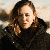 a woman wearing a black jacket and hoop earrings