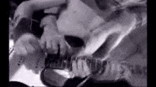 a black and white photo of a man playing an electric guitar .