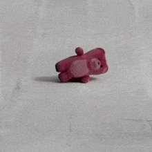a pink teddy bear is laying in the snow near a fence