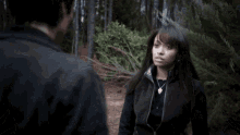 a man in a black jacket is standing in the woods