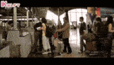 a group of people are standing in an airport with a kulfy logo on the bottom