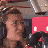 a woman wearing headphones and a microphone looks to the left