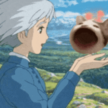a girl is holding a cat with its mouth open in front of a field .