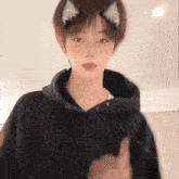 a young man wearing a black hoodie and cat ears on his head