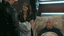 a man and a woman are standing next to an older man in a hospital bed