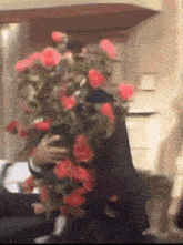 a man in a suit is holding a bouquet of red roses .