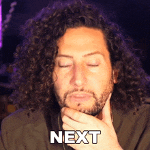 a man with curly hair and a beard has his eyes closed and the word next is on his face