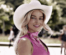 a woman wearing a cowboy hat and a pink dress smiles for the camera