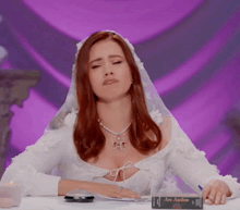 a woman in a wedding dress is sitting at a table with a book on it that says aec amber