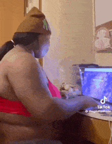 a woman is sitting at a desk playing a video game on a laptop computer .