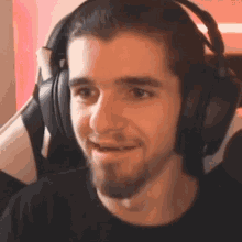 a man with a beard is wearing headphones and making a face .