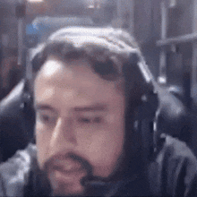 a man with a beard wearing headphones and a microphone is sitting in a chair .