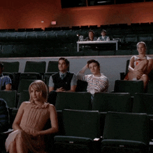 a group of people are sitting in a theatre watching a show