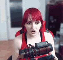 a woman with red hair is sitting in front of a microphone and making a surprised face .