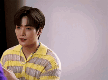 a young man wearing a yellow and gray striped sweater