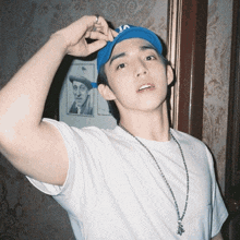 a man wearing a white shirt and a blue hat with the letter a on it