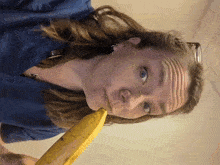 a woman in a blue scrub top bites into a banana