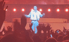 a man is singing into a microphone in front of a crowd of people