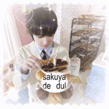a man in a suit and tie is eating a cake that says " sakuya de dul " on it