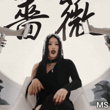 a woman in a black dress is surrounded by hands holding cell phones and the letters ms are on the bottom right